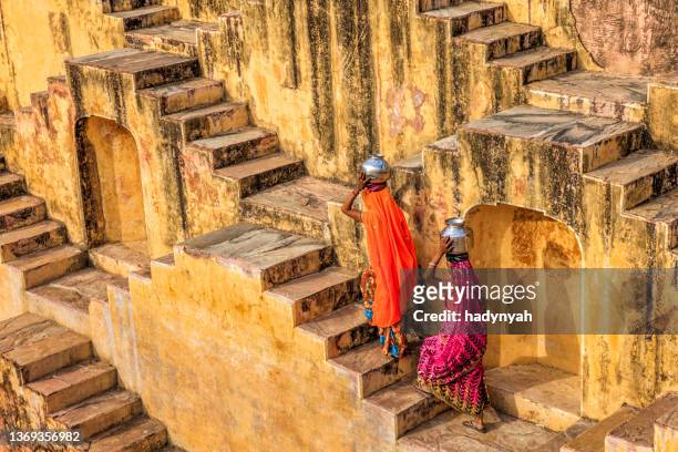 indische frauen, die wasser aus stepwell bei jaipur transportieren - third world stock-fotos und bilder