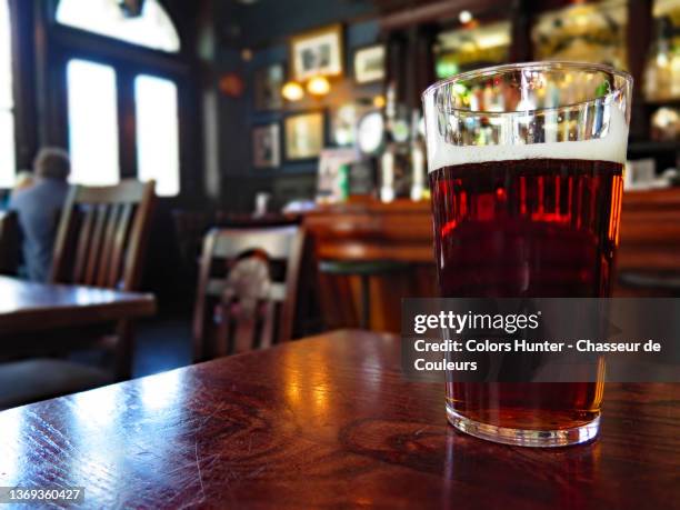 a glass of beer in a london pub with blurred background - british pub stock-fotos und bilder