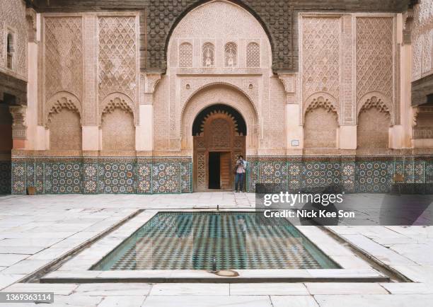 female tourist preparing to take photographs in the stunning ben youssef madrasa courtyard - madrassa - fotografias e filmes do acervo