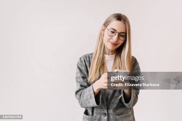 a student in casual clothes prints an online message and does online shopping using a mobile phone and wireless technology on a white background. a business woman in a jacket communicates using a smartphone. online education . millennial life - woman smiling white background stock-fotos und bilder