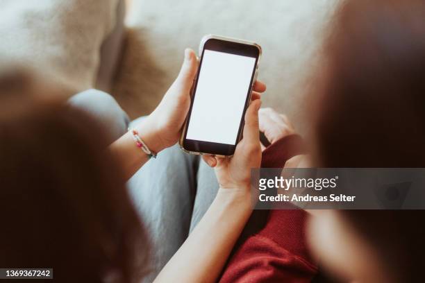 girl showing mobile phone screen to another woman - showing smartphone stock pictures, royalty-free photos & images