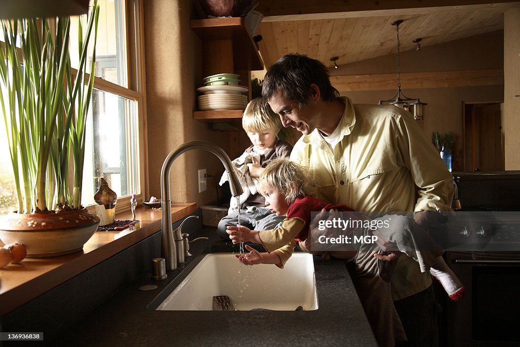 Father with young children at sink