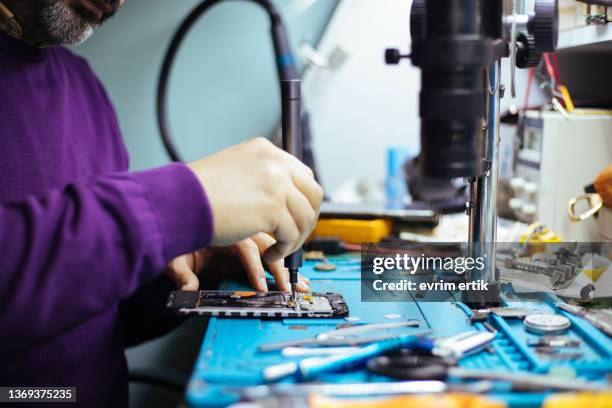 technician disassembling smartphone with screwdriver. - mobile services stock pictures, royalty-free photos & images