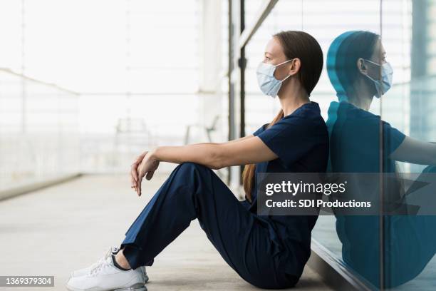 still wearing protective mask, operating room female nurse takes break - nurse thinking stock pictures, royalty-free photos & images