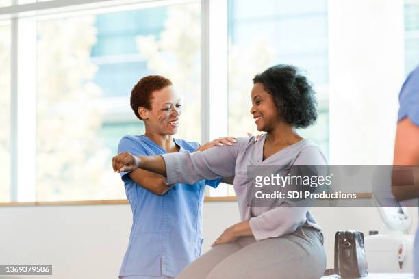 therapist and female patient smile during shoulder massage - kinesist stockfoto's en -beelden