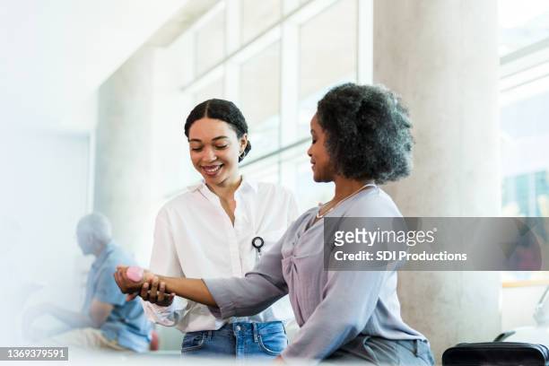 therapeut lächelt, während er die handgewichtsübungen der geschäftsfrau leitet - occupational therapist stock-fotos und bilder