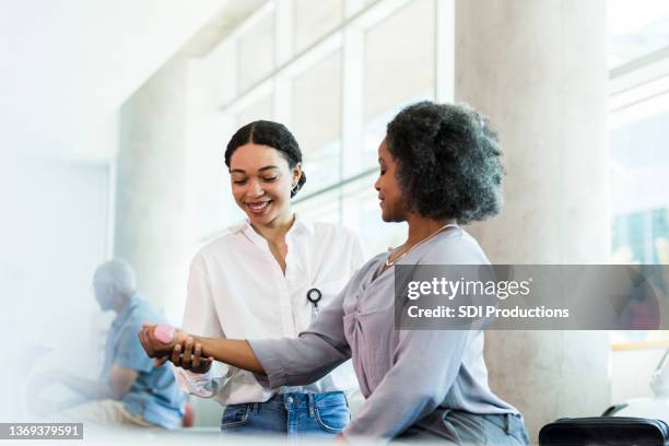 terapeuta sorri ao orientar exercícios de peso da mão da empresária - terapia ocupacional - fotografias e filmes do acervo