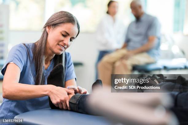 female therapist massages unrecognizable man's injured foot - male group therapy stock pictures, royalty-free photos & images