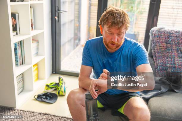 mature man checking his smartwatch after a run - runner tired stock-fotos und bilder