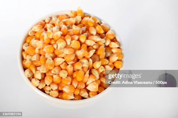 close-up of dried corn in clay pot,close-up of corn kernels in bowl against white background - corn kernel stock-fotos und bilder