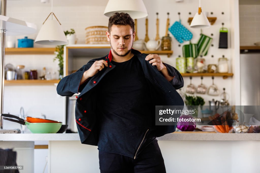 Joven chef poniéndose su uniforme antes de preparar la comida