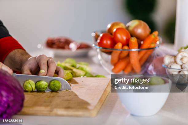 unrecognizable chef chopping brussel sprouts on a cutting board - brussel sprout stock pictures, royalty-free photos & images