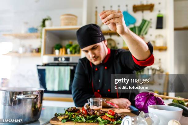 chef adding a pinch of salt on a dish he prepared - adding salt stock pictures, royalty-free photos & images