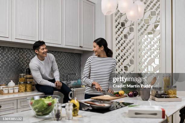 young multiracial couple at home, cooking in kitchen - flores indonesia - fotografias e filmes do acervo