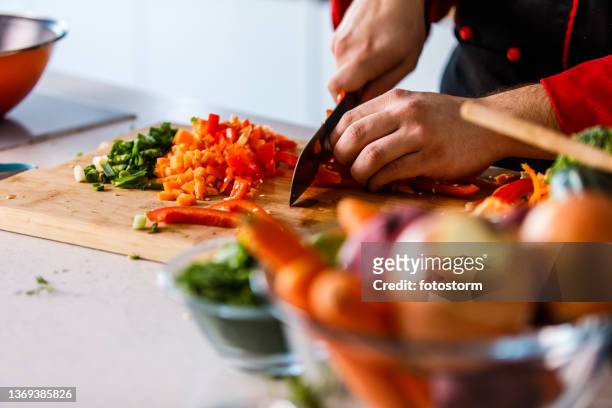 toma de enfoque selectivo del chef cortando en cubitos un pimiento rojo - mirepoix comida fotografías e imágenes de stock