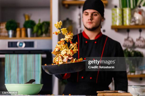 professioneller koch sautiert fliege pasta mit sauce - angebraten stock-fotos und bilder