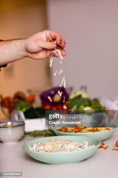chef sprinkling fresh parmesan cheese on top of pasta - strooisels stockfoto's en -beelden