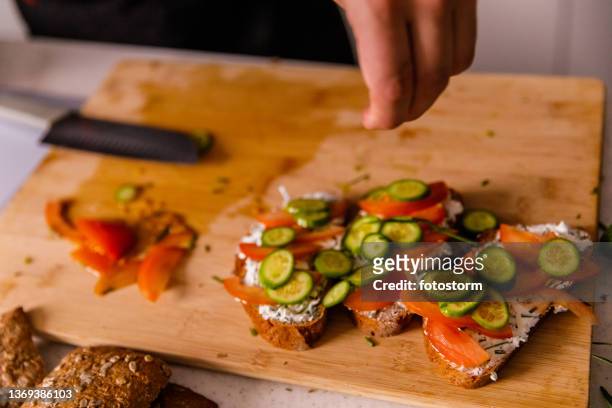chef adicionando sal em cima de sanduíches que ele está fazendo - adicionar sal - fotografias e filmes do acervo