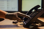 Phone scam and night theft by criminal hacker on telephone call. Man hand in a black glove with a phone on a dark background