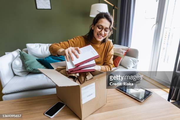 young woman unpacking online purchase at home - debit cards credit cards accepted 個照片及圖片檔