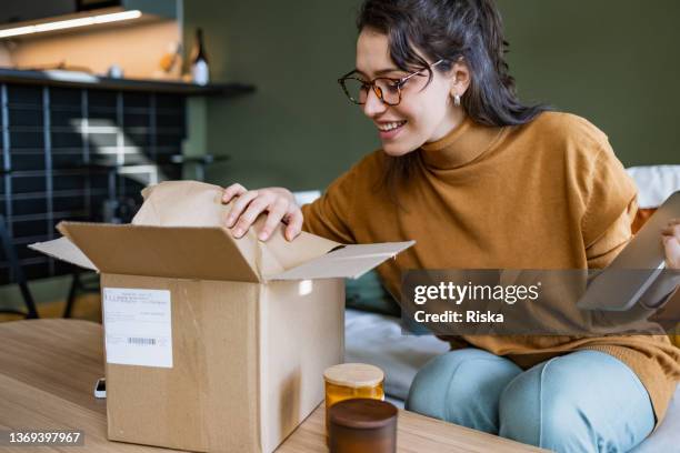 mujer sonriente abriendo una caja de parto - recibir fotografías e imágenes de stock