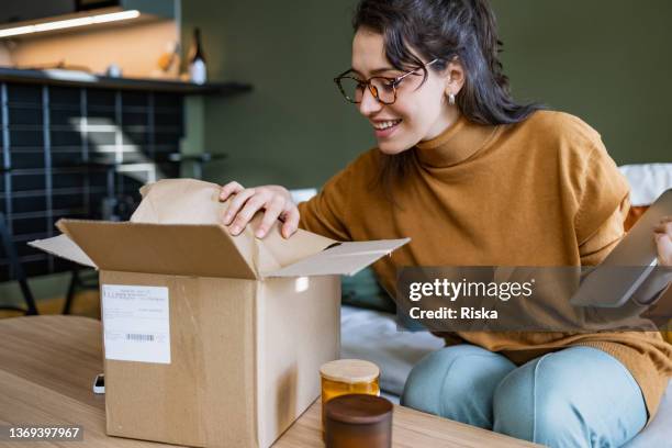 smiling woman opening a delivery box - package imagens e fotografias de stock