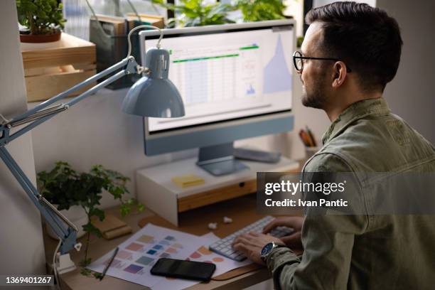 rear view of a young caucasian man working from home using a desktop pc - effortless stock pictures, royalty-free photos & images