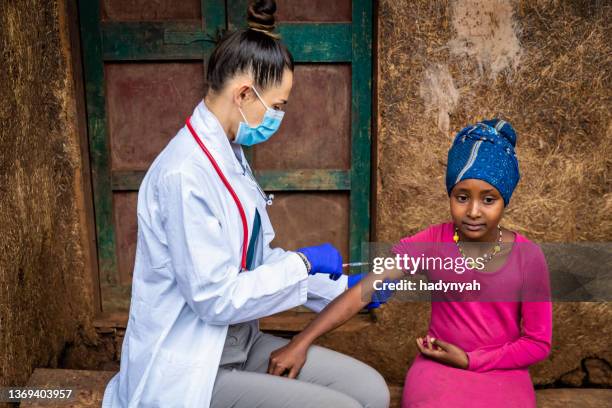 female doctor is doing an injection to young african girl in small village, east africa - médicos sem fronteiras imagens e fotografias de stock