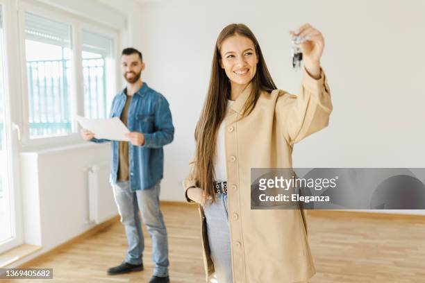 portrait of a happy couple holding the keys to their new house and looking at the camera smiling - real estate concepts - home key stockfoto's en -beelden