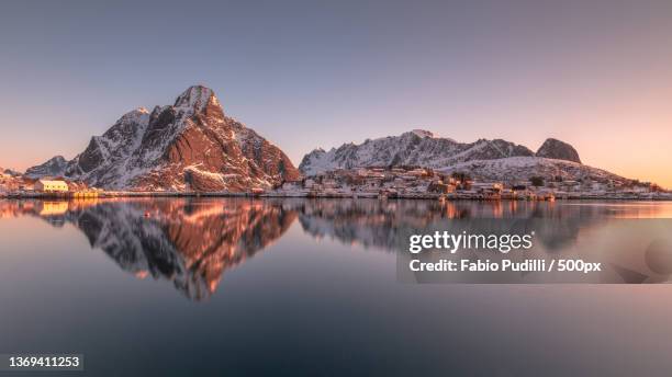 sunrise reflections,scenic view of lake by mountains against clear sky during sunset,reine,nordland,norway - norway landscape stock pictures, royalty-free photos & images