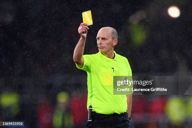 Match referee Mike Dean shows a yellow card to Josh Brownhill of Burnley during the Premier League match between Burnley and Manchester United at...