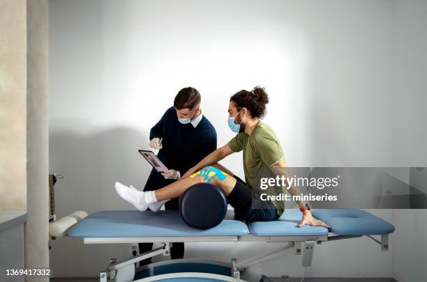 fisioterapeuta segurando um tablet com gráfico de anatomia e explicando o problema ao paciente (espaço de cópia) - prevenção de doenças - fotografias e filmes do acervo