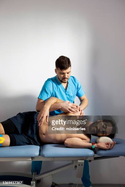 fisioterapista che esamina e regola la spalla del paziente - osteopata foto e immagini stock