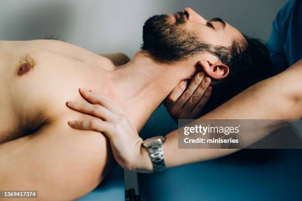 anonymous chiropractor adjusting patient's neck - osteopathie stockfoto's en -beelden