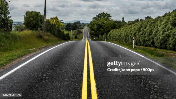 long road,empty road amidst trees against sky,hamilton,new zealand - hamilton neuseeland stock-fotos und bilder