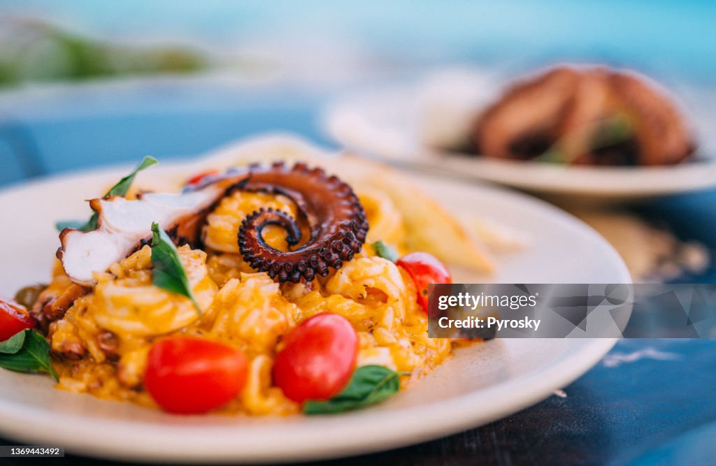 Risotto with octopus tentacle and a grilled octopus served on the table