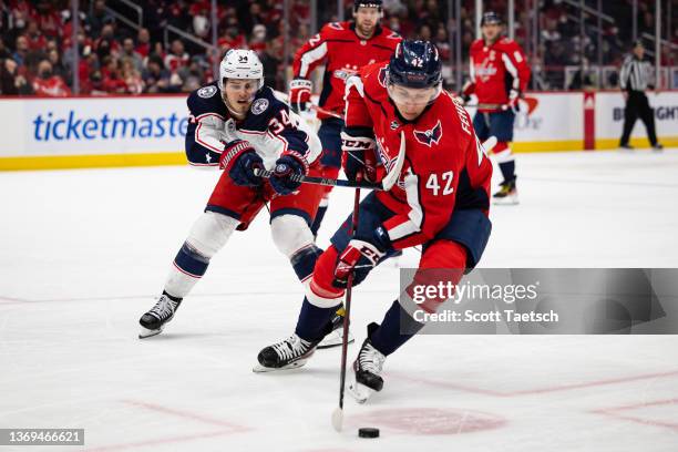 Martin Fehervary of the Washington Capitals and Cole Sillinger of the Columbus Blue Jackets vie for the puck during the third period of the game at...