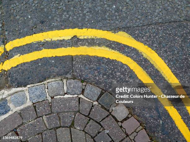 yellow lines painted on a street  and along a sidewalk in london - linea gialla foto e immagini stock