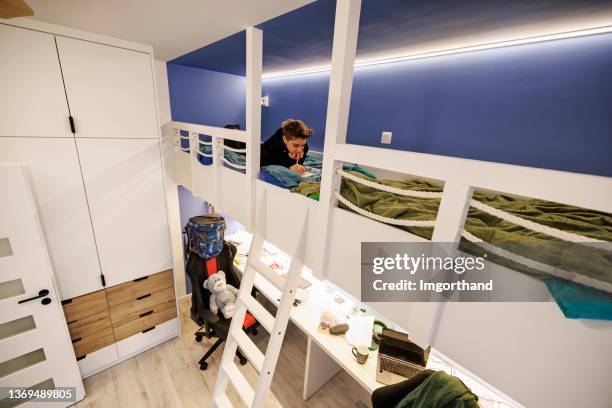 teenage boy lying in bed and studying for school - kids in bunk bed stock pictures, royalty-free photos & images