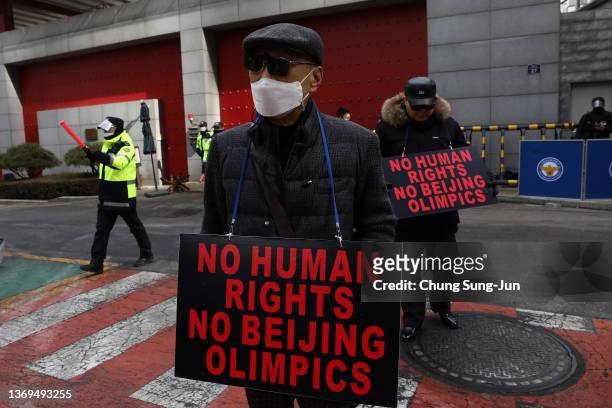 Protesters hold placards reading, "No Human Rights, No Beijing Olympics," during an anti-Olympics rally in front of the Chinese Embassy on February...