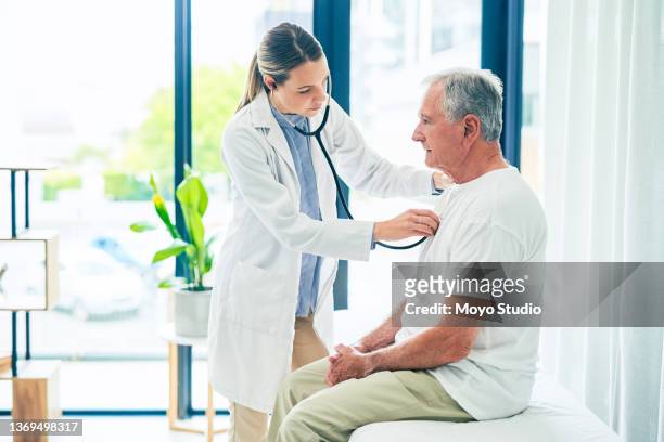 aufnahme einer ärztin, die einem patienten eine brustuntersuchung gibt - stethoskop stock-fotos und bilder
