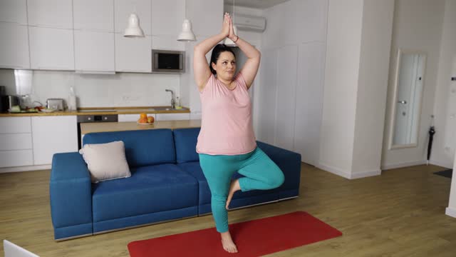 Overweighted woman performing yoga asana at home