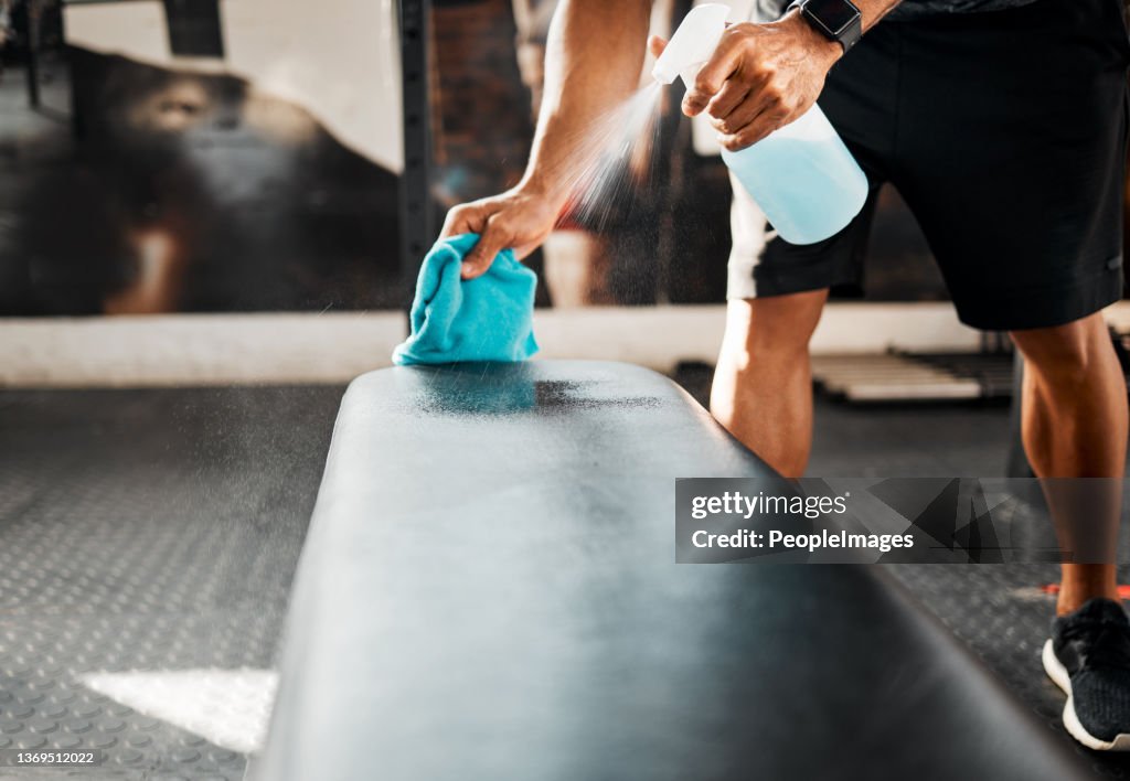 Shot of a business owner sanitizing the work benches in their gym