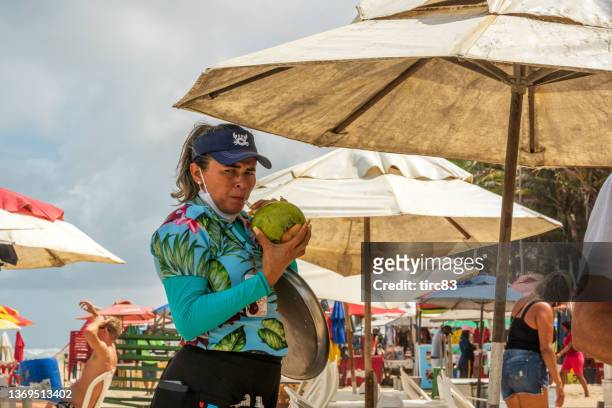 waitress drinking coconut water between serving holidaymakers at fortuna beach in fortaleza - coconut beach woman stock pictures, royalty-free photos & images