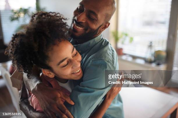 mature african american father hugging his teenage daughter at home. - black teen girl stock-fotos und bilder