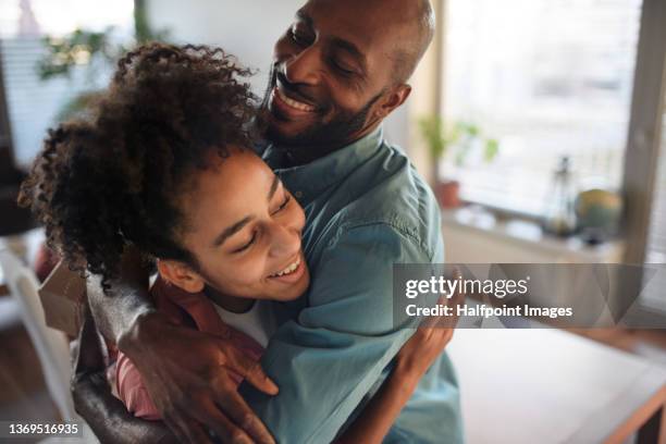 mature african american father hugging his teenage daughter at home. - black girls fotografías e imágenes de stock