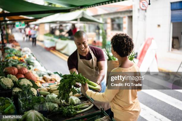 market seller showing the vegetables to customer - street market stock pictures, royalty-free photos & images