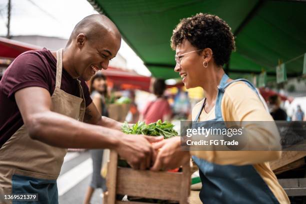 coworkers carrying boxes at a street market - straatverkoper stockfoto's en -beelden