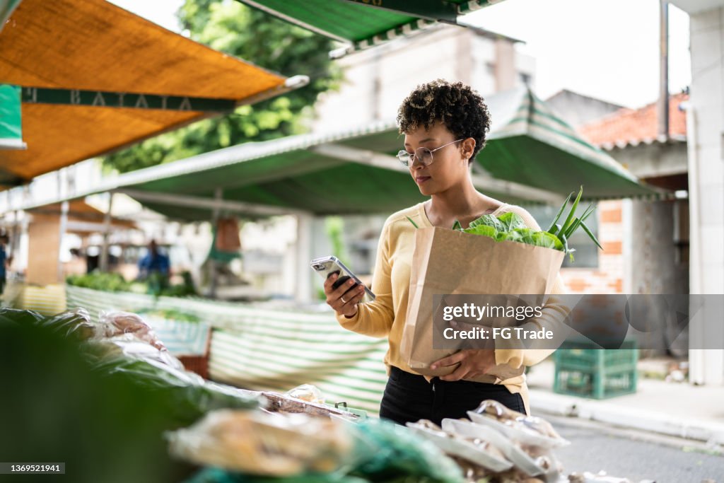 Junge Frau mit dem Handy auf einem Straßenmarkt