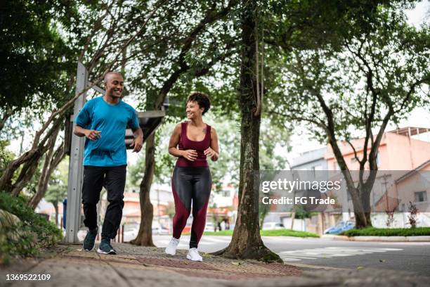 young couple running in the street - corrida de rua imagens e fotografias de stock